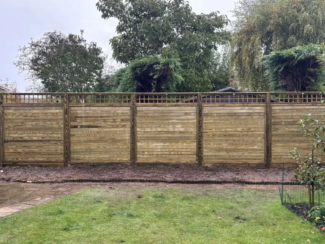 Horizontal slatted fence with a trellis top along a lawn