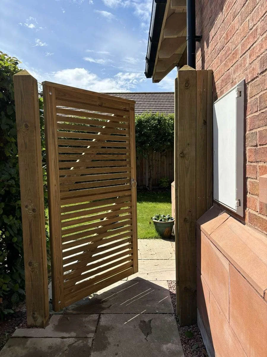 Open slatted timber side gate beside a brick house