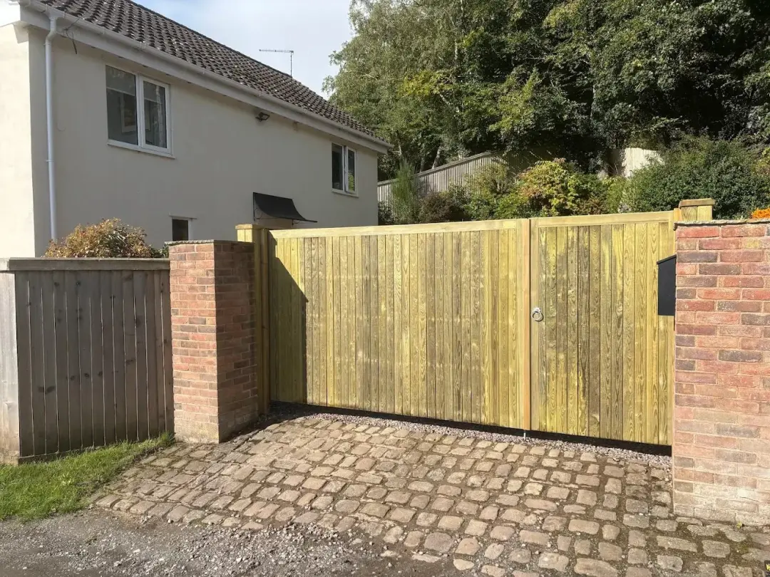 Timber driveway gate across a cobbled drive